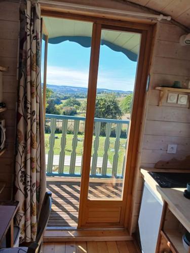 a door in a cabin with a view of a balcony at Roulotte du Touton avec jacuzzi in Preignan