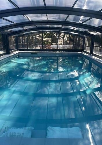 une grande piscine d'eau bleue dans un bâtiment dans l'établissement Sous Le Cerisier, à Amélie-les-Bains-Palalda