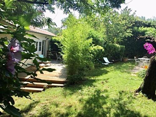 une arrière-cour avec une maison et une cour ornée d'arbres et de fleurs dans l'établissement Sous Le Cerisier, à Amélie-les-Bains-Palalda