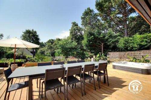 a table with chairs and an umbrella on a deck at Villa Namasté SPA Hammam port & Mer in La Trinité-sur-Mer