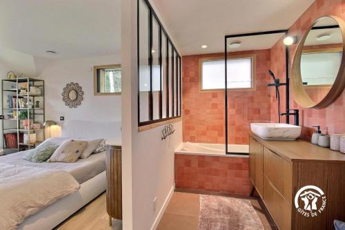 a bedroom with a bed and a tub and a sink at Villa Namasté SPA Hammam port & Mer in La Trinité-sur-Mer