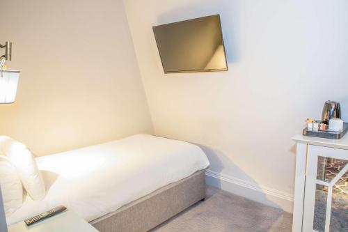 a small bedroom with a bed and a tv on the wall at Henrietta House, a member of Radisson Individuals in Bath