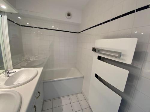 une salle de bain blanche avec un lavabo et une baignoire dans l'établissement Superbe appartement vue mer 4 personnes, à Merlimont