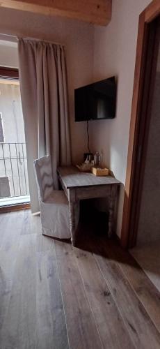 a living room with a table and a chair and a television at B&B Piccolo Relais in Lessolo