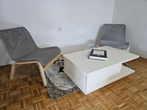 two chairs and a table with a book on it at Violeta guest house in Petrovaradin