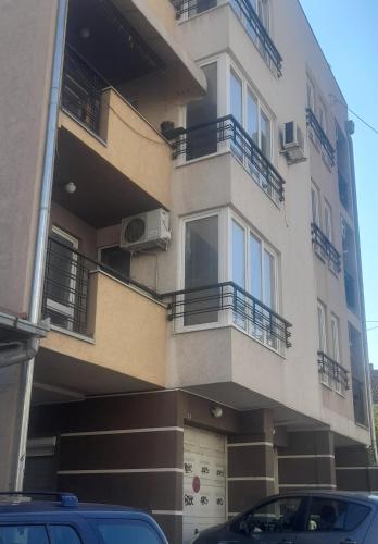 a building with balconies and cars parked in front of it at Apartman Talija in Kragujevac
