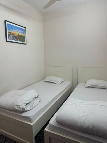 two beds in a room with a picture on the wall at Hotel In Need - Near to the US France Italy Saudi Embassy and Airport in Dhaka