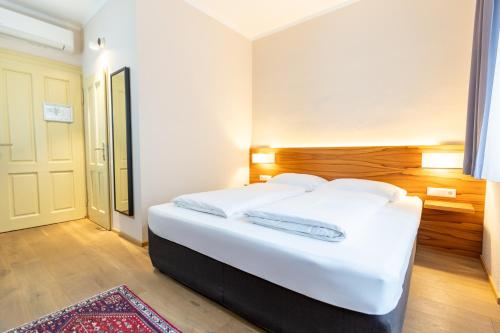 a bedroom with a large white bed with white sheets at Das Jedermann Boutiquehotel mit Stadtgarten in Salzburg
