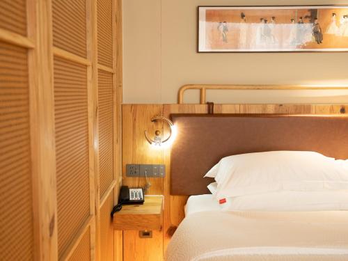 a bedroom with a bed and a phone on a table at Patio Spring Holiday Inn -- Free round trip pick-up service --Panoramic view of Tianmen Mount in Zhangjiajie