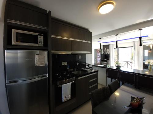 a kitchen with a black refrigerator and a table at Pousada Recanto do Aconchego in Florianópolis