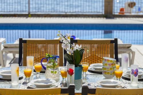a table with plates and glasses of orange juice and flowers at Meneou Beachfront Villa Sunset in Perivolia