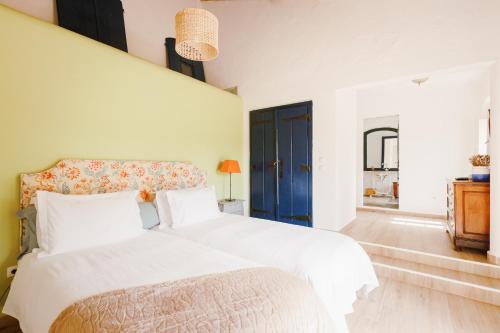 a bedroom with a white bed and a blue door at Monte do Ramalho in Avis