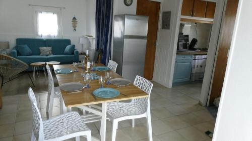 une table de salle à manger avec des chaises et une cuisine dans l'établissement Chalet, à Gruissan