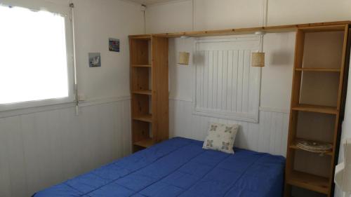 - une chambre avec un lit doté de draps bleus et d'étagères dans l'établissement Chalet, à Gruissan