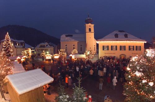 a group of people standing in front of a building with christmas lights at Pension Schlömmer in Sankt Gilgen