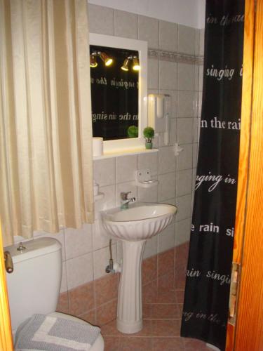 a bathroom with a white toilet and a sink at Boussetil Rooms CapAnMat in Tinos Town