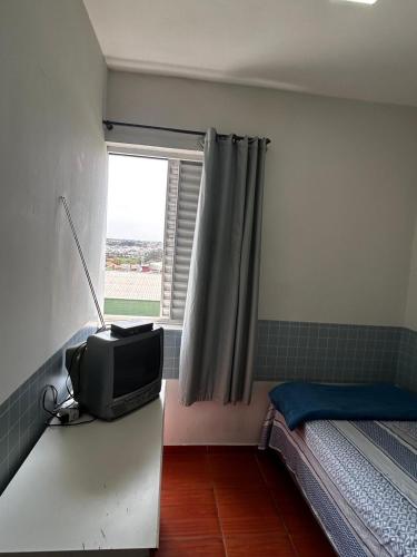 a bedroom with a tv on a counter with a window at Hospedagem Recanto Miriam -Salto in Salto