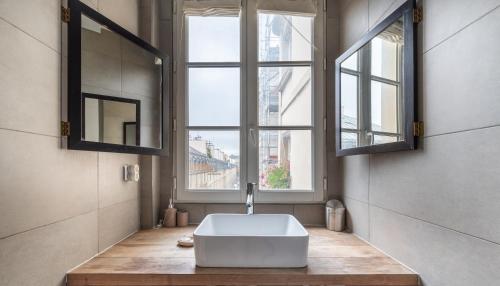 La salle de bains est pourvue d'une baignoire et de 2 fenêtres. dans l'établissement Stylish 1BD Duplex - Stunning Views near Louvre, à Paris