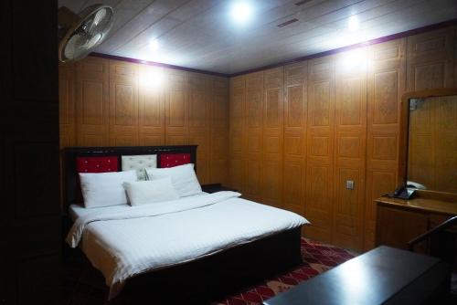 a bedroom with a bed with wooden walls and lights at Hotel Dewanekhas Skardu in Skardu