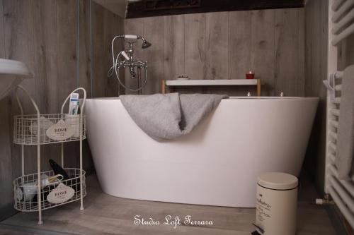 フェラーラにあるSTUDIO LOFT FERRARA centro storico vista castelloの木製の壁のバスルーム(白いバスタブ付)