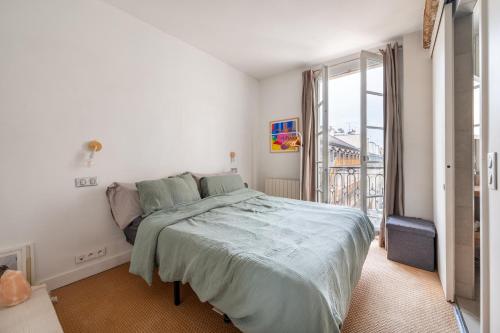 une chambre avec un grand lit et une grande fenêtre dans l'établissement Stylish 1BD Duplex - Stunning Views near Louvre, à Paris