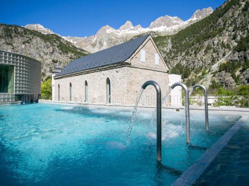 una iglesia con una fuente de agua frente a un edificio en Alojamientos Ruraltena, en Piedrafita de Jaca