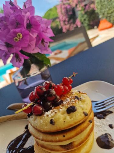 a plate with a stack of pancakes with fruit on top at La Villa Monarque in Cap d'Agde