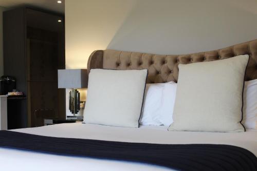a bedroom with a bed with white pillows at Thornton Hall Hotel & Spa in Heswall
