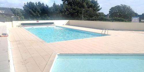 - une piscine d'eau bleue sur du carrelage dans l'établissement Maisonnette 2 pièces Mezzanine 4 pers avec piscine extérieure chauffée ADELA, à Guidel