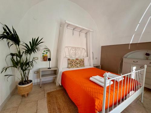 une chambre avec un lit orange et une plante dans l'établissement DIMORA MOLINI, à Monopoli