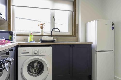 a kitchen with a washing machine and a window at Cochran House in Bathgate