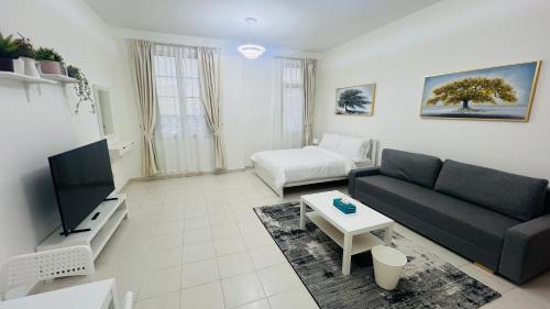 a living room with a couch and a tv at France cluster International city - Spacious Bright Furnished Studio apartment in Dubai