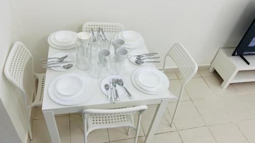 a white table with white plates and silverware on it at France cluster International city - Spacious Bright Furnished Studio apartment in Dubai