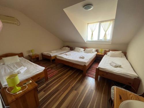 a room with three beds and a window at Aranykalász Panzió in Szentes