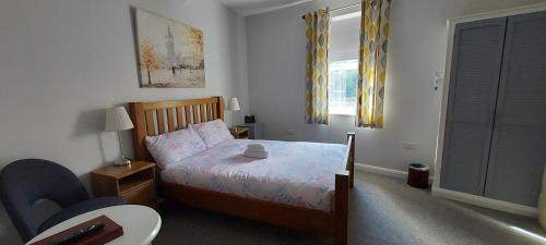 a bedroom with a bed and a table and a window at Southwell Stays in Southwell