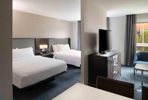 a hotel room with two beds and a flat screen tv at Homewood Suites By Hilton Boston Logan Airport Chelsea in Chelsea
