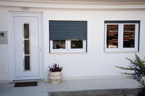 a white house with a door and two windows at Casa das Pôpas in A dos Cunhados