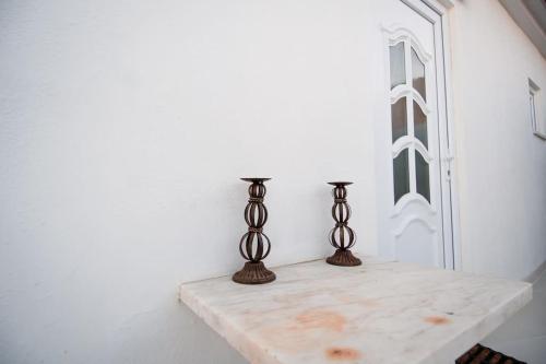 two metal candlesticks sitting on a table next to a door at Casa das Pôpas in A dos Cunhados