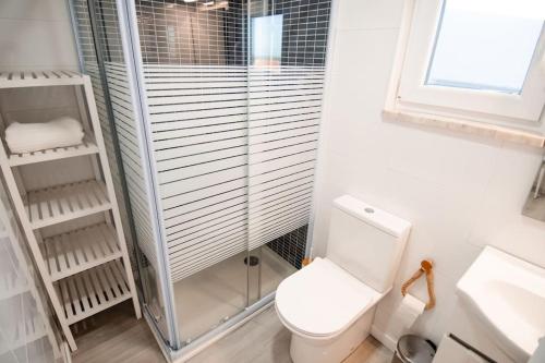 a bathroom with a toilet and a glass shower at Casa das Pôpas in A dos Cunhados