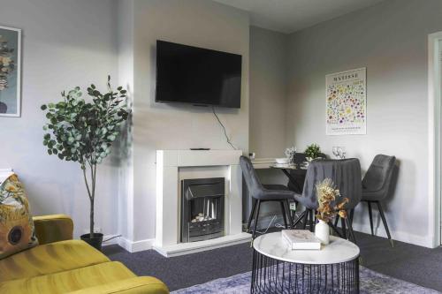 a living room with a table and a television above a fireplace at Pentland House in Bathgate