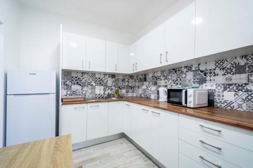 a kitchen with white cabinets and a microwave at GrowIN Stay Mercado in Faro