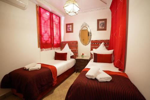 two beds in a room with red curtains at Palais Zahia Hotel & Spa in Tangier