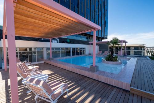 a deck with chairs and a swimming pool on a building at The Rose 602: Modern City Apartment with Views in Cape Town