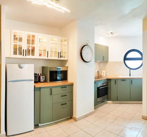 une cuisine avec des placards verts et une horloge murale dans l'établissement Appartement 6 personnes face à la mer, à Cagnes-sur-Mer