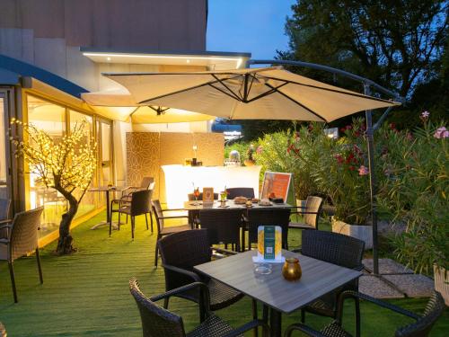 a patio with tables and chairs and an umbrella at Best Western Air Hotel Linate in Segrate