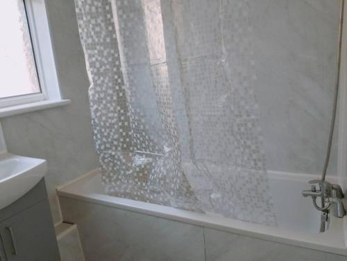 a shower with a glass shower curtain in a bathroom at Budget-Friendly 4-Bedroom House in Swansea - Ideal for Travelers in Swansea