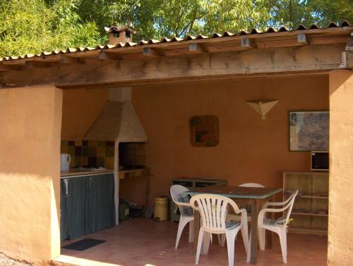 un patio avec une table et des chaises et une cuisine dans l'établissement La Genestière, à Clermont-lʼHérault