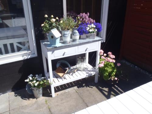 a white table with flowers on it next to a window at Oddevej 20 Skagen in Skagen