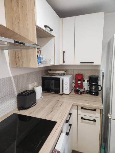 une cuisine avec des armoires blanches et un micro-ondes dans l'établissement Agréable appartement rénové situé dans les hauteurs de Brides, à Brides-les-Bains
