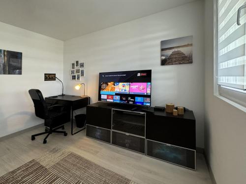 a living room with a desk and a flat screen tv at Chez Vélia Grand 4 pièces, parking privé et emplacement idéal in Strasbourg